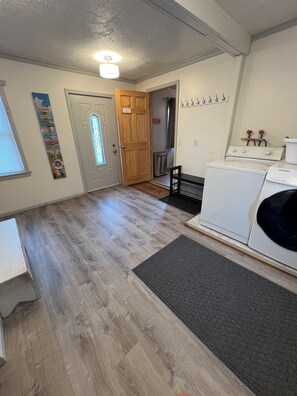A laundry room with a washing machine, a dryer, a door with a sign, and a wall-mounted heater. - Cozy updated 3 BR home steps away from downtown, space to relax and enjoy.  (Holland)