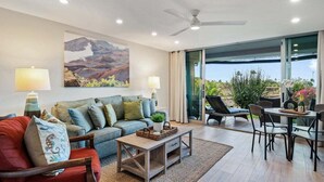 A modern living room with a sofa, coffee table, and chairs. There is a large window with a view of the outdoors. - Spacious 1BD w Exclusive Beach Cabana - Maui Eldorado K104 (Lahaina)