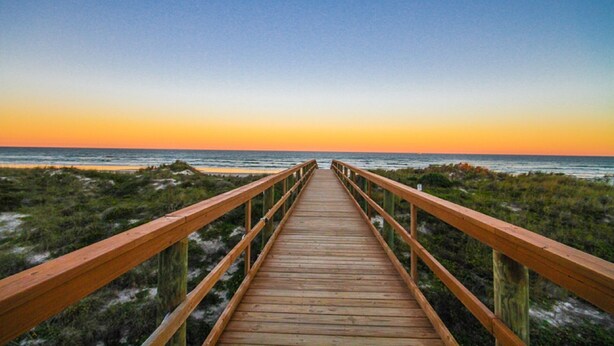 A wooden boardwalk leading to the beach with a clear view of the ocean and a sunset in the background. - Direct Oceanfront Condo and Drive on the beach access!! (Saint Augustine)