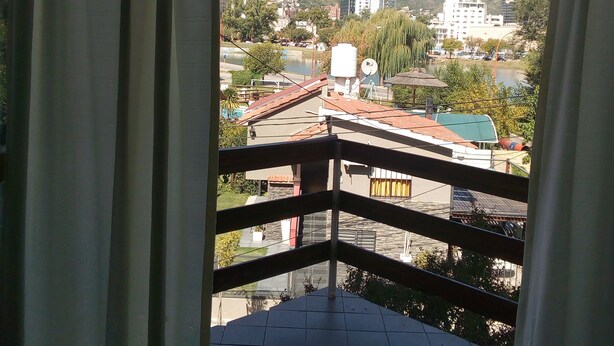 A balcony with a view of a cityscape, including buildings and a hill. - Departamento Temporario (Villa Carlos Paz)
