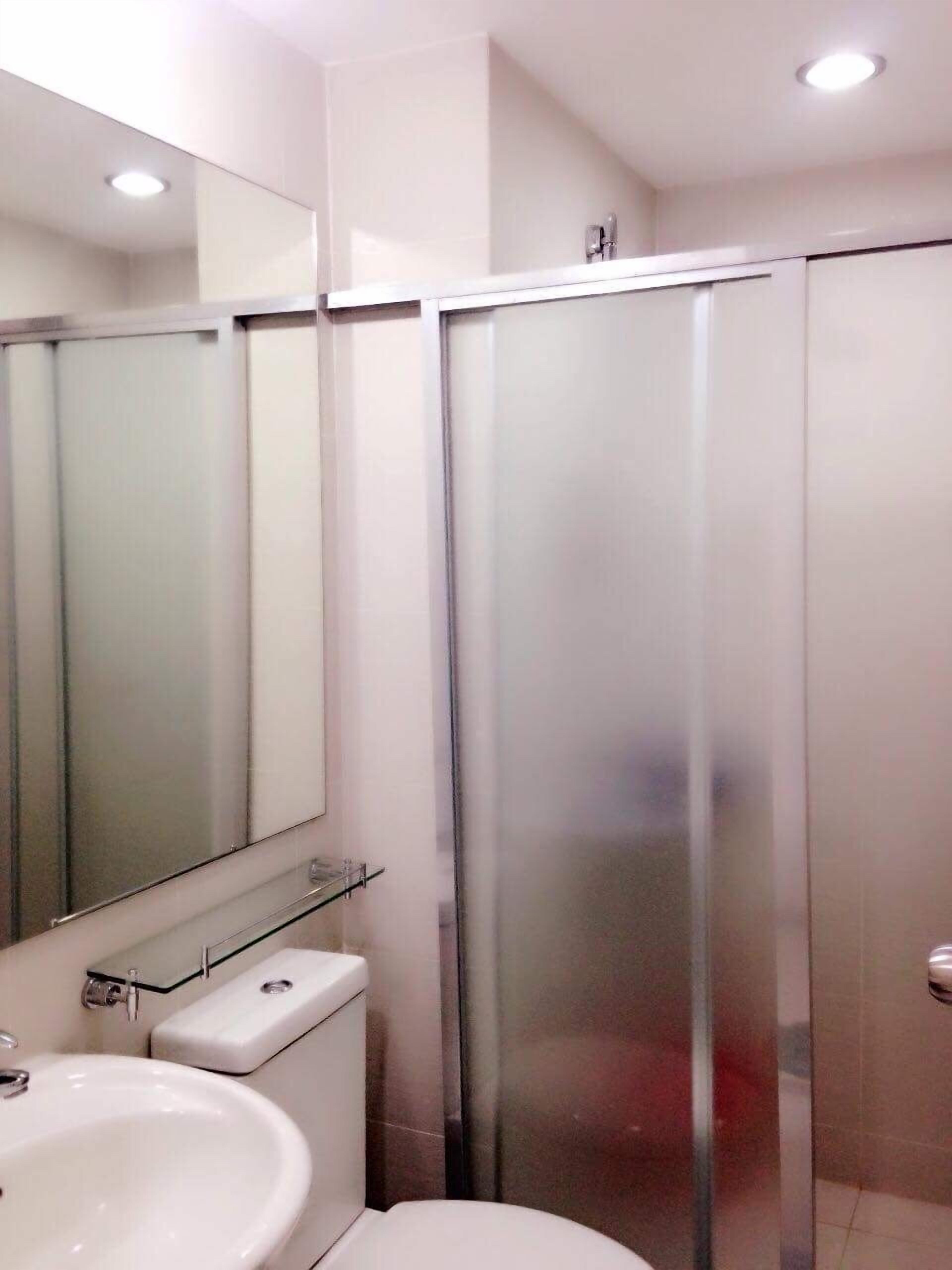 Un baño con inodoro, lavamanos y cabina de ducha de vidrio.