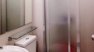 Un baño con inodoro, lavamanos y cabina de ducha de vidrio.