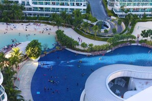 A large outdoor swimming pool with multiple lanes, surrounded by palm trees and a modern building. - Azure Residences Condominium Daily Rental (Parañaque)