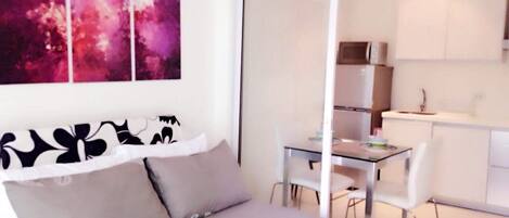 A modern bedroom with a bed, a dining table, and a kitchenette.