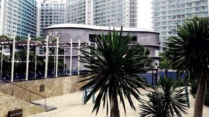 A modern hotel with multiple high-rise buildings, a curved structure in the foreground, and palm trees. - Azure Residences Condominium Daily Rental (Parañaque)