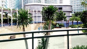 A modern building with a curved facade, surrounded by palm trees and a pool area. - Azure Residences Condominium Daily Rental (Parañaque)