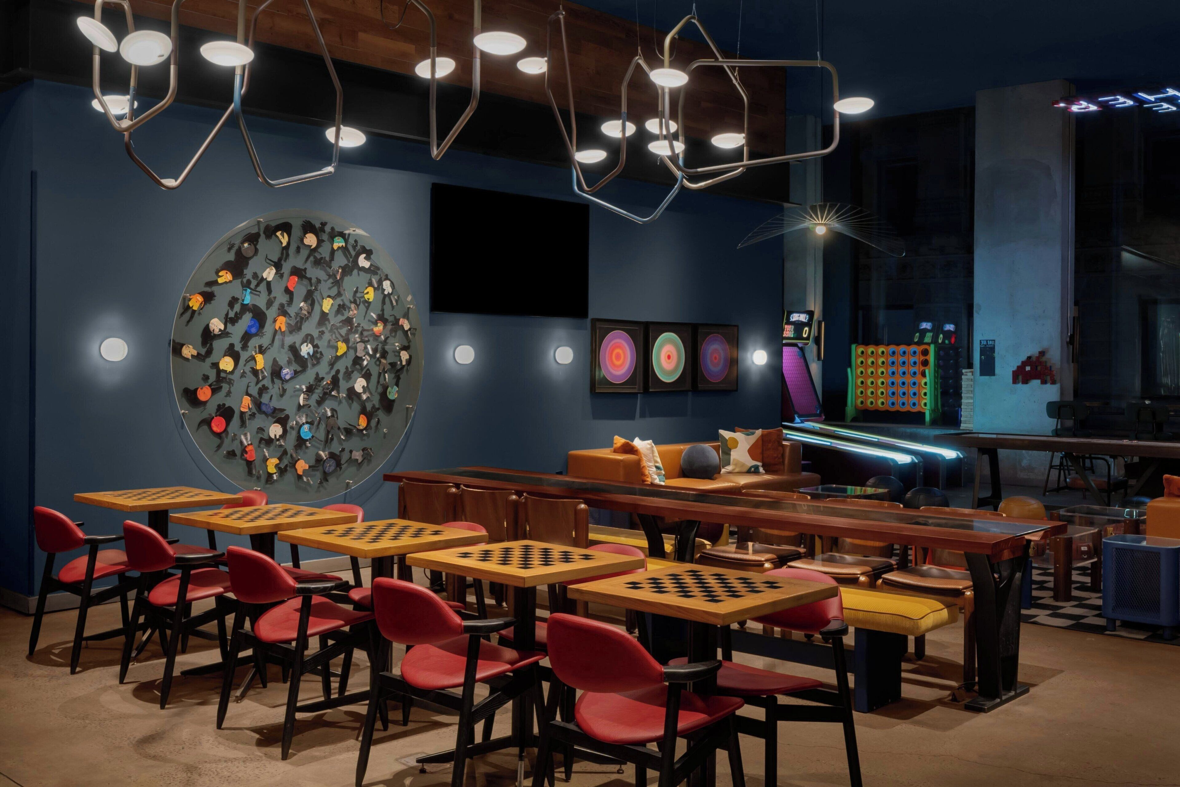 A modern lounge with hexagonal ceiling lights, a large circular wall art piece, and a neon sign.