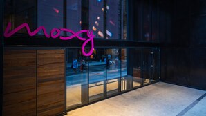 A modern building with a glass facade and a neon sign reading "Moxy". - Moxy NYC Downtown (New York)