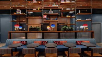 Un área de lounge moderna con un sofá azul, varias mesas redondas y una variedad de objetos en estantes de madera.