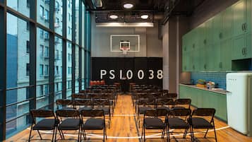 A conference room with rows of chairs, a basketball hoop, and a kitchen area with cabinets.