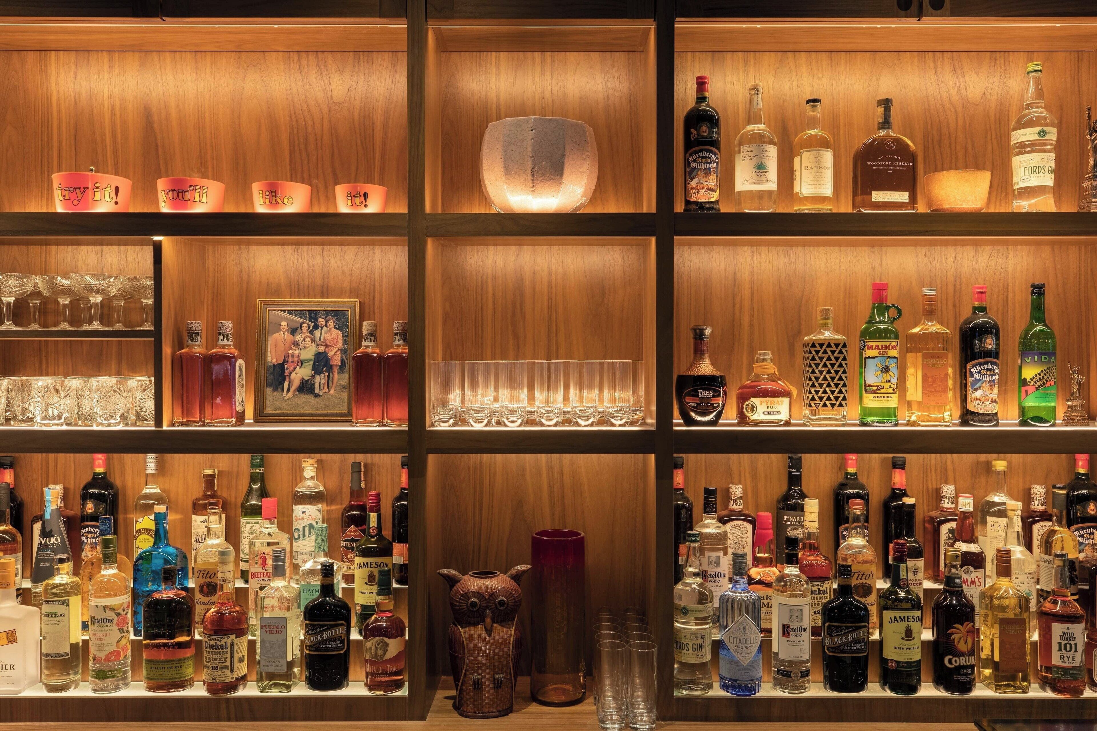 A bar area with shelves stocked with various liquor bottles and glasses.