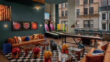 A modern lounge area with a checkered floor, sofas, and a pool table.