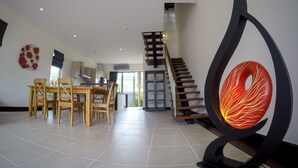A spacious living area with a dining table and chairs, a staircase, and a unique decorative sculpture.