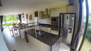 A modern kitchen with a central island, stainless steel appliances, and a dining area with a view of the outdoors.