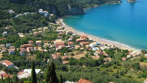 A coastal town with a beach, houses, and a prominent rock formation. - Beachfront holiday house Eftichia (Agios Gordios)