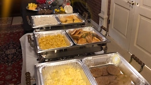 A buffet table with various food items in trays, a statue, and a door in the background. - Trucountry Inn (Brady)