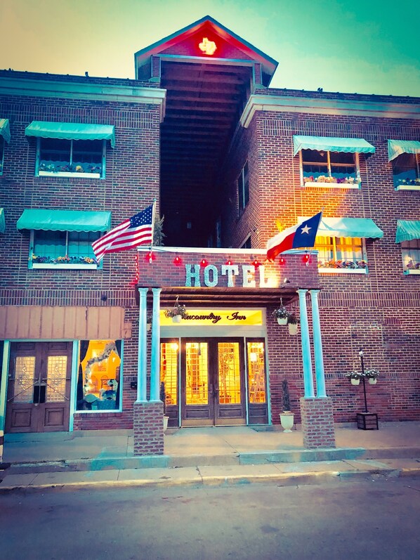 Ein Hotel mit Backsteinfassade, zwei amerikanischen Flaggen und einem Schild mit der Aufschrift 'Hotel'.