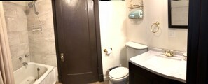 Ein Badezimmer mit Badewanne, Toilette, Waschbecken und Duschkopf.