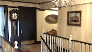 A staircase with white balusters and a wooden handrail, leading to a landing with a chandelier and framed artwork. - Trucountry Inn (Brady)