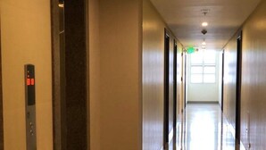 A modern hallway with a digital elevator display, a clean floor, and a bright exit at the end. - Favila Condotel Unit at 101 Newport Boulevard (Pasay)