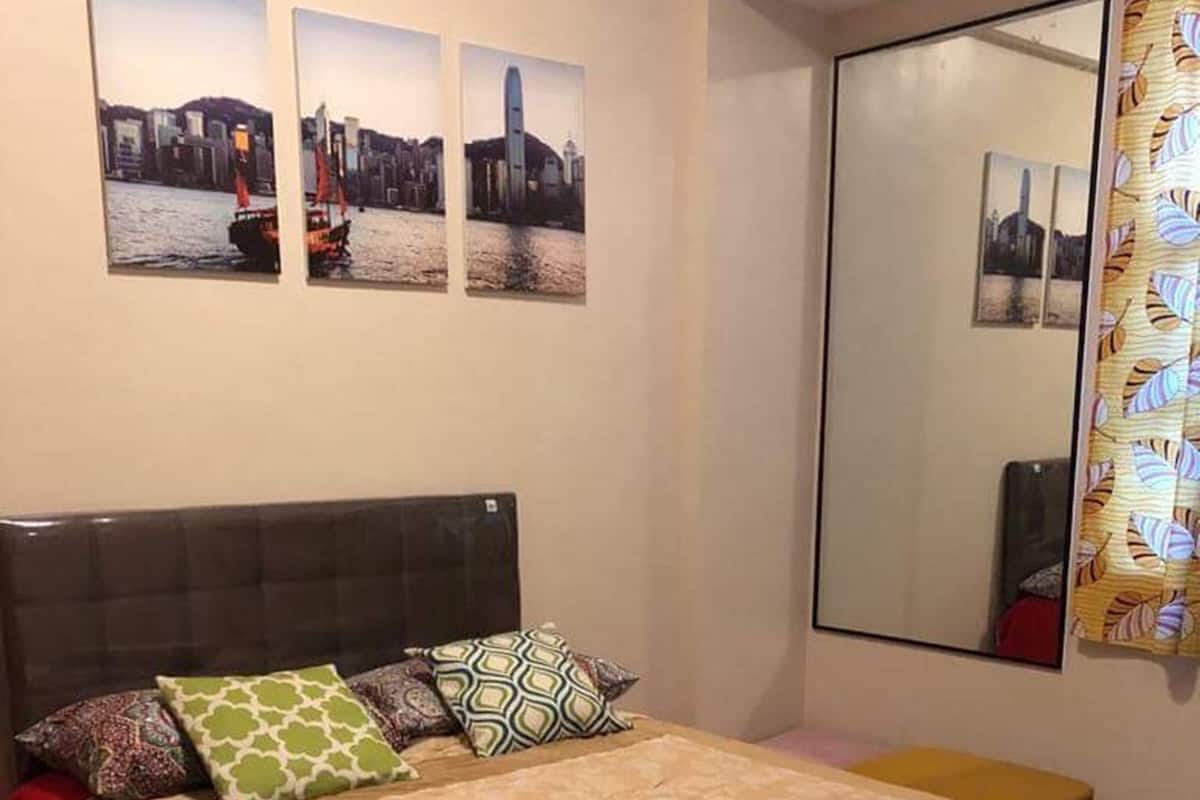 Ein Schlafzimmer mit einem großen Bett, einem Kopfteil, vielen Kissen, einem Nachttisch, einem Spiegel und drei Stadtansichten an der Wand.