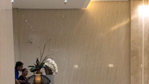 A modern lobby with a reception desk, a vase with flowers, and a marble wall. - Favila Condotel Unit at 101 Newport Boulevard (Pasay)