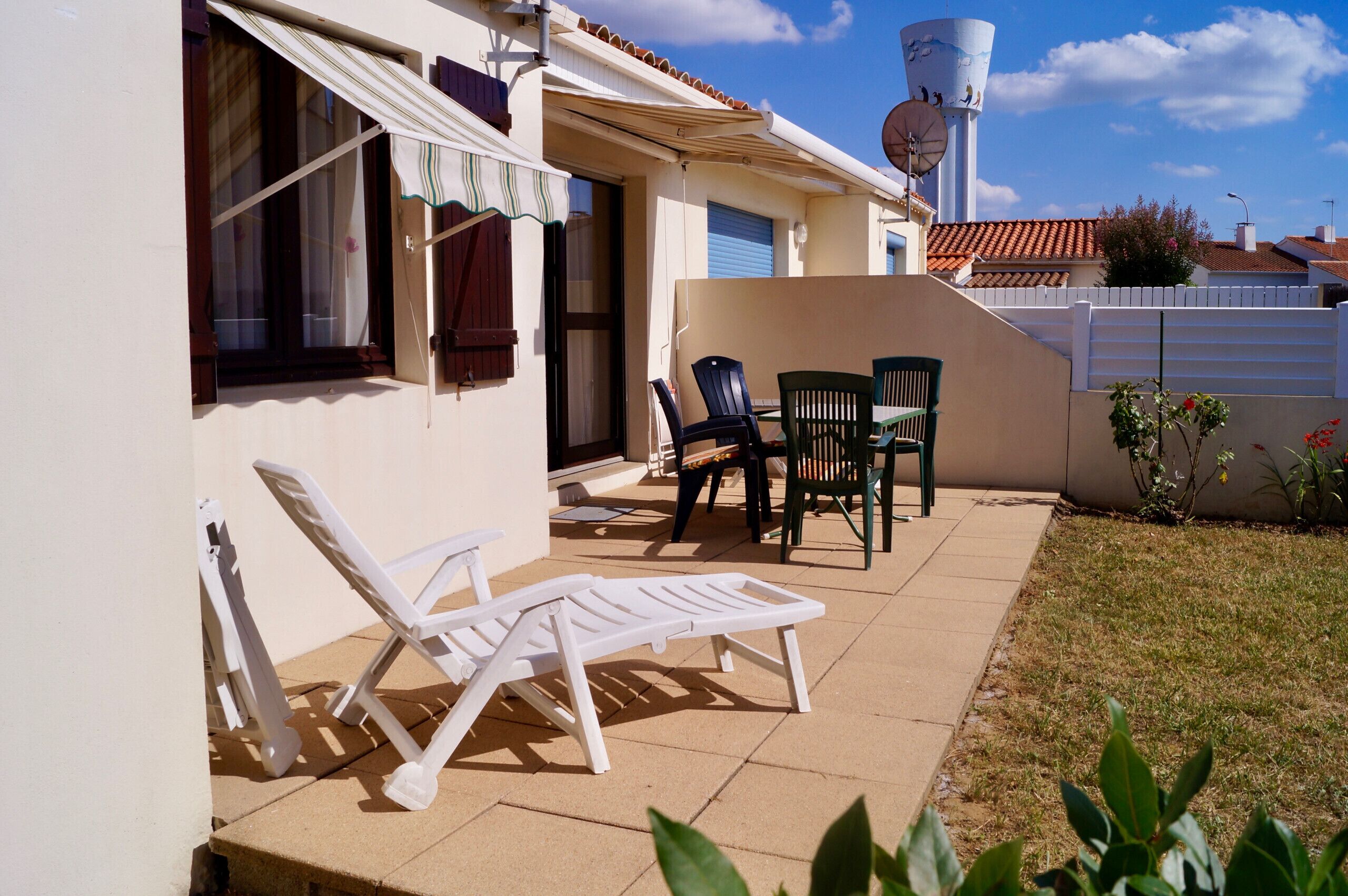 A patio with lounge chairs, a table, and a small garden area.