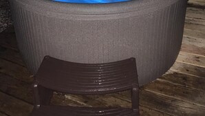 Een jacuzzi met een houten terras en een houten omheining op de achtergrond.