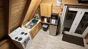 Een kleine keuken met houten wanden, een fornuis, een koelkast en een magnetron.