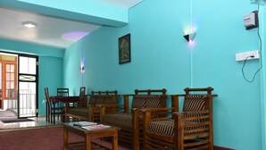 Una habitación con paredes verde azulado, sillas de madera con cojines a rayas, una mesa de madera y una puerta que da al exterior.