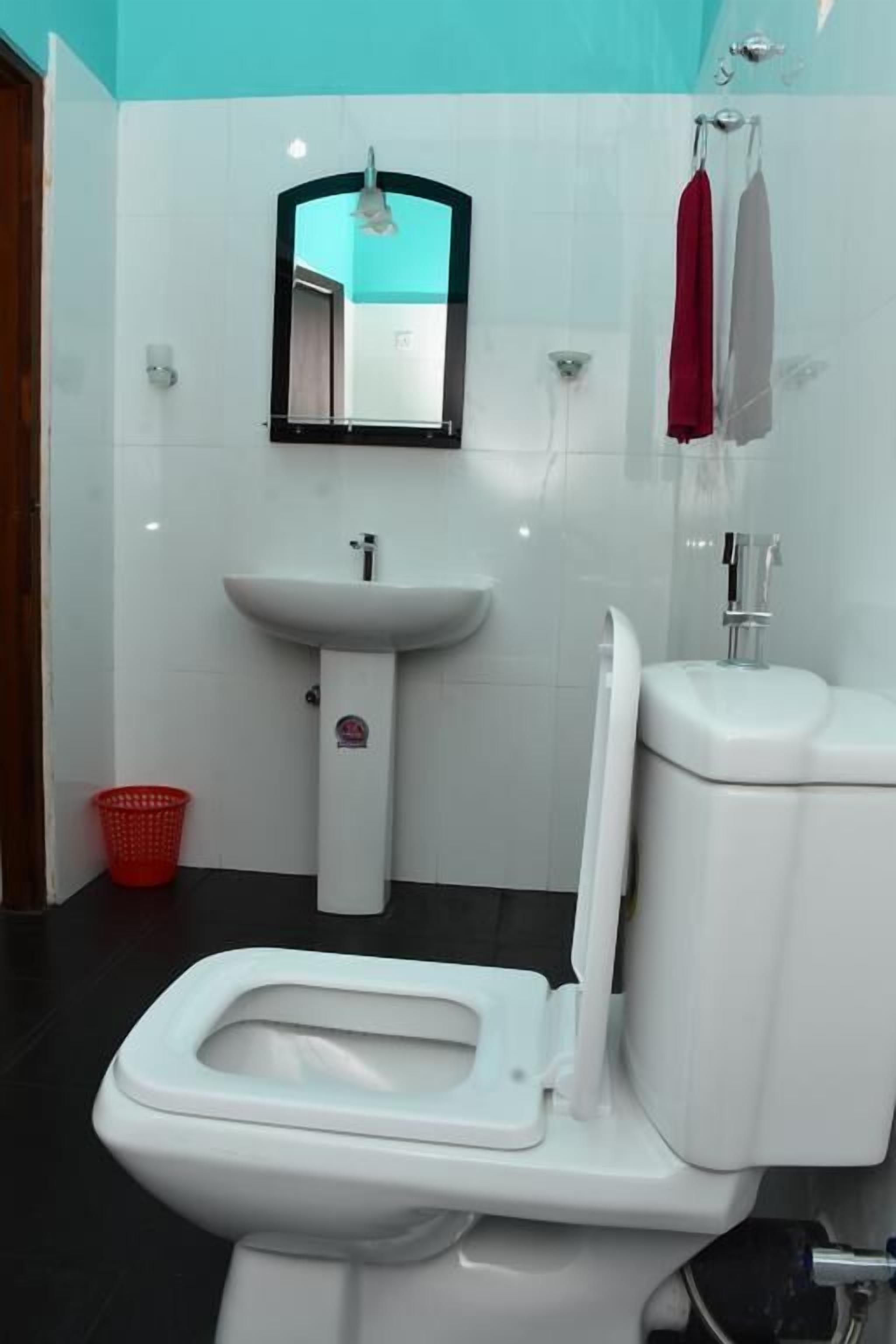 Une salle de bain avec des toilettes blanches, un lavabo et un miroir.