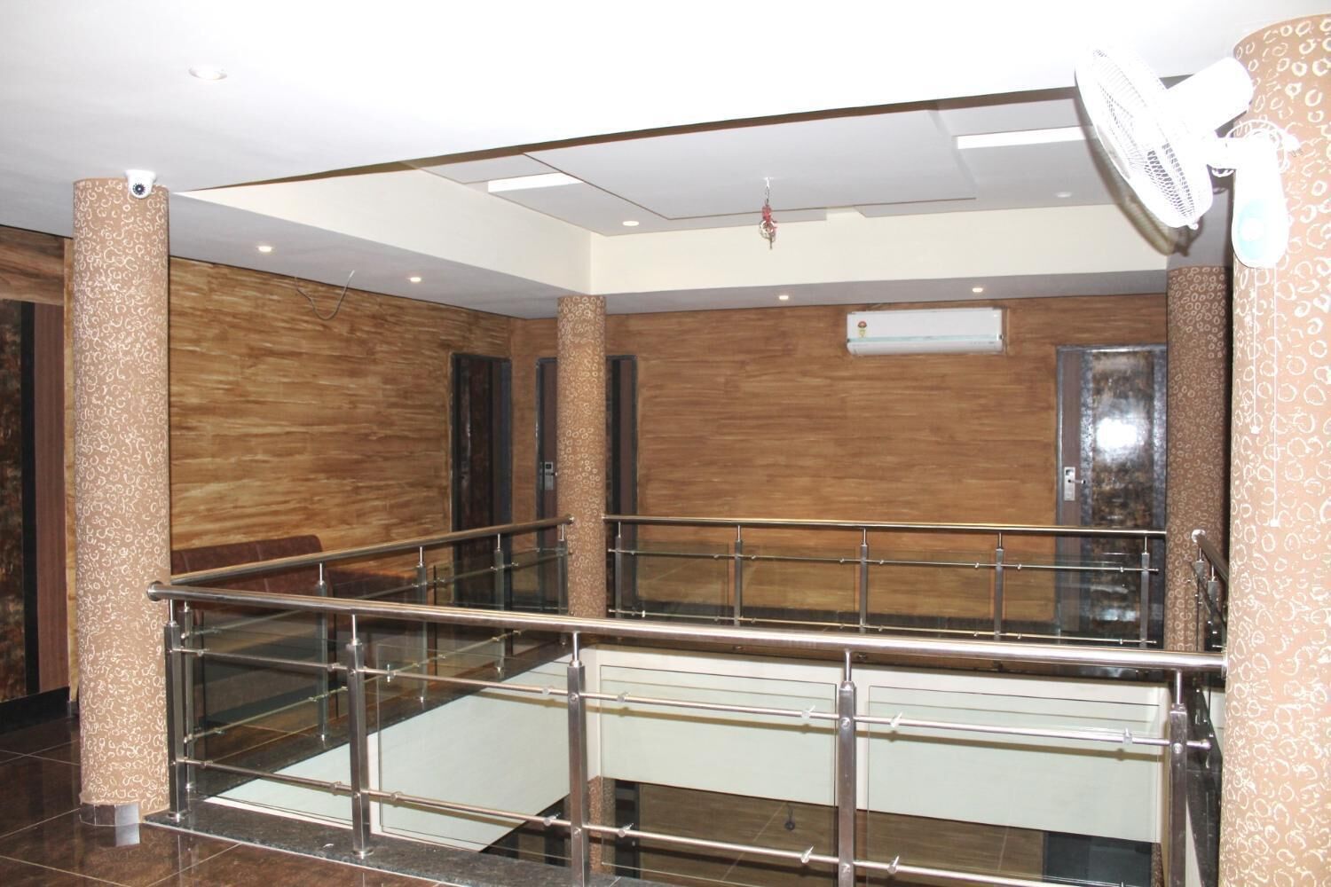 Un vestíbulo amplio con barandilla de vidrio, paredes de madera y un ventilador de techo.