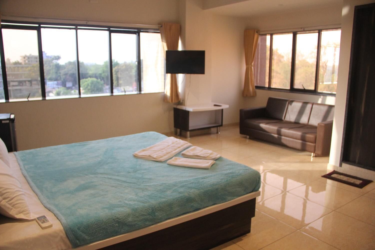 A hotel room with a bed, a TV, a sofa, and a desk.