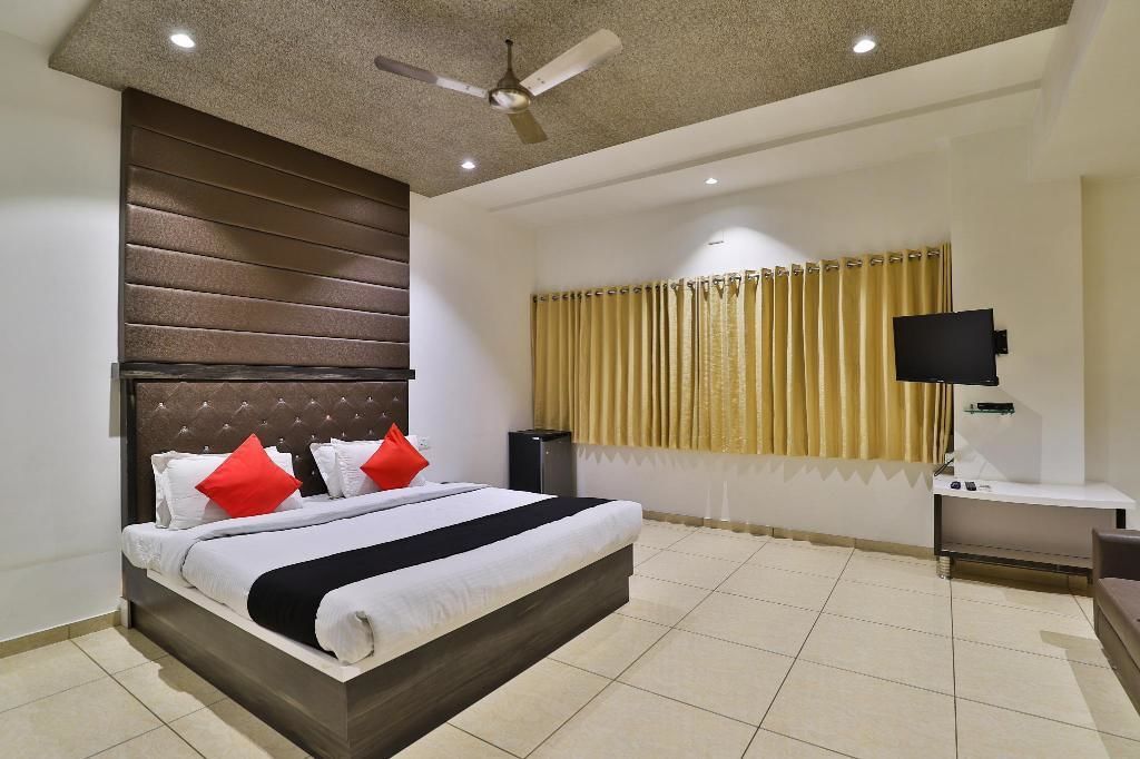 A modern hotel room with a large bed, a ceiling fan, a flat-screen TV, and a window with curtains.