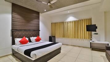 A modern hotel room with a large bed, a ceiling fan, a flat-screen TV, and a window with curtains.