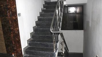 A staircase with black steps and metal handrails, leading to a landing with a dark-framed window.