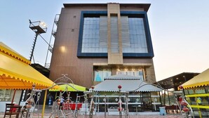 A modern building with a large glass facade and a central entrance. - Dev Motel & Banquet (Nadiad)