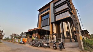 A modern building with a multi-story structure, large windows, and a covered entrance area. - Dev Motel & Banquet (Nadiad)
