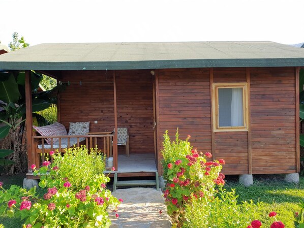 Une cabane en bois avec une véranda, une petite table et deux chaises.