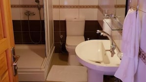 Un baño con ducha, inodoro, lavamanos y un perchero para toallas.