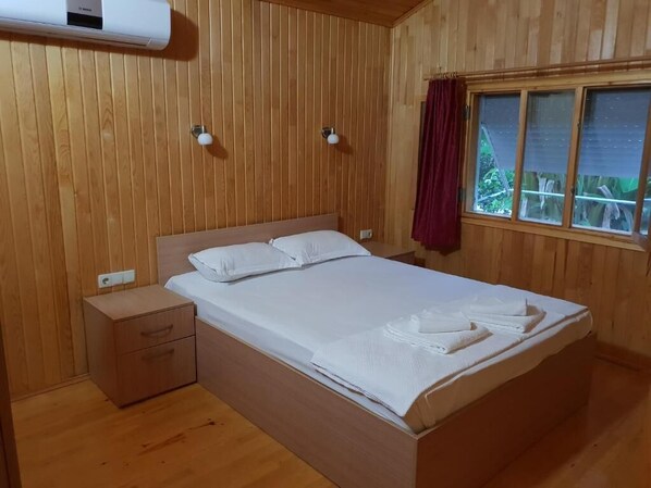 A wooden-paneled room with a bed, a nightstand, and a window with curtains. - Estelar Bungalow (Kemer)
