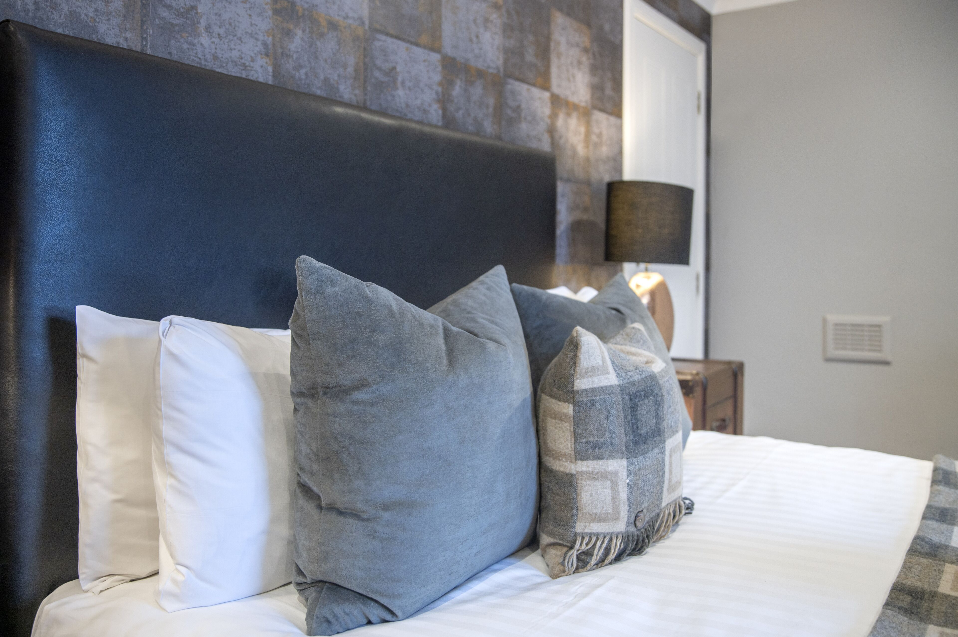 A neatly made bed with multiple pillows and a headboard.
