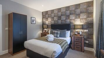 A bedroom with a bed, a wardrobe, a dresser, and a textured wall.