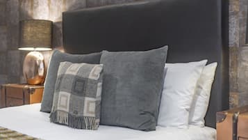 A bed with a black headboard, grey and white pillows, and a patterned throw blanket.