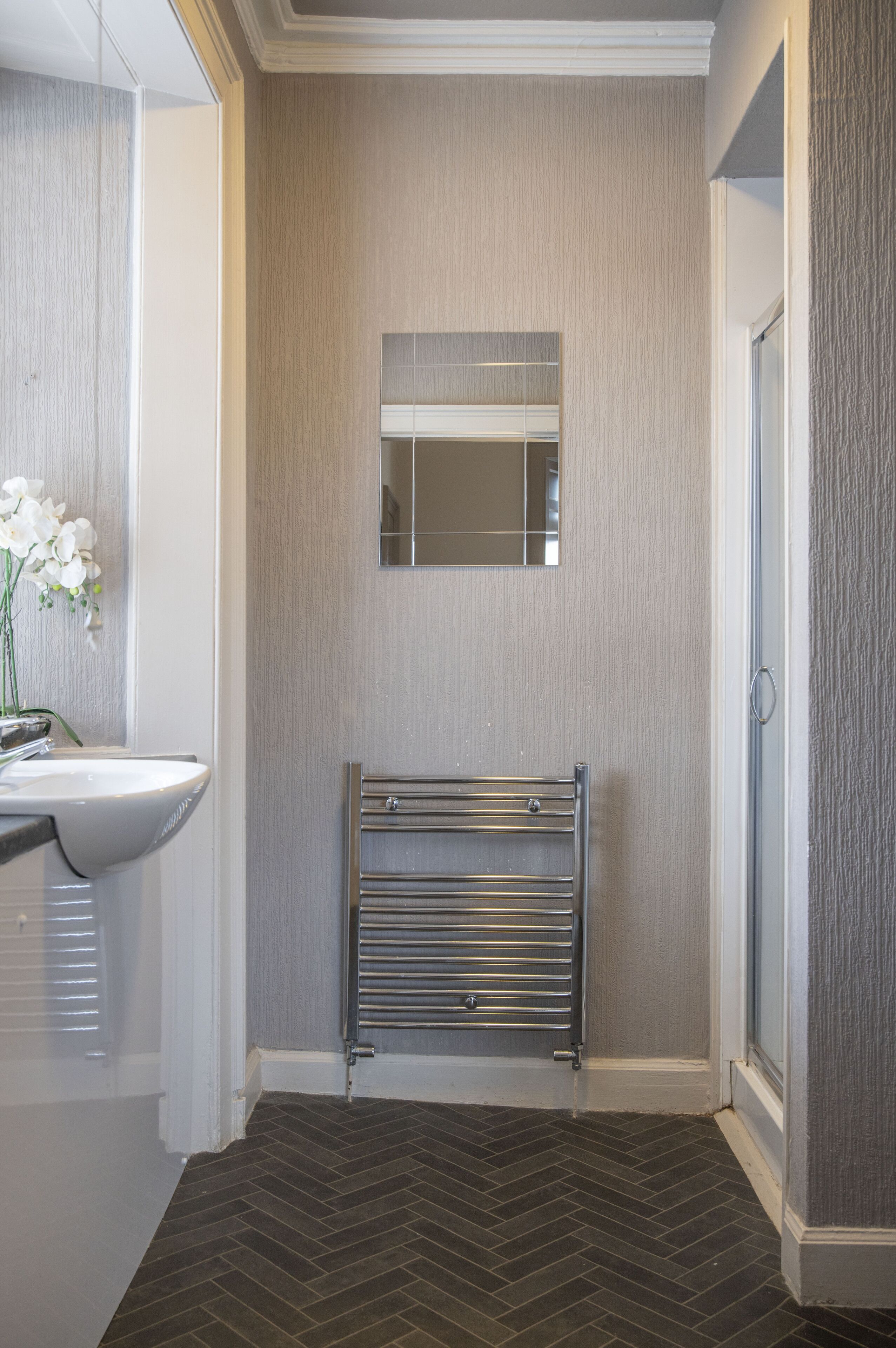A bathroom with a white sink, a mirror, and a towel rack.