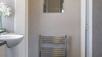 A bathroom with a white sink, a mirror, and a towel rack.