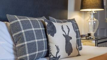Un lit avec deux oreillers, l’un à motifs écossais et l’autre orné de la silhouette d’un cerf.