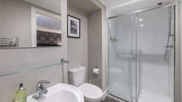 Ein modernes Badezimmer mit Duschkabine aus Glas, einem weißen Waschbecken und einer Toilette.