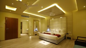 A modern bedroom with a large bed, bedside tables, a ceiling fan, and recessed lighting. - Wood Note Thekkady (Peermade)