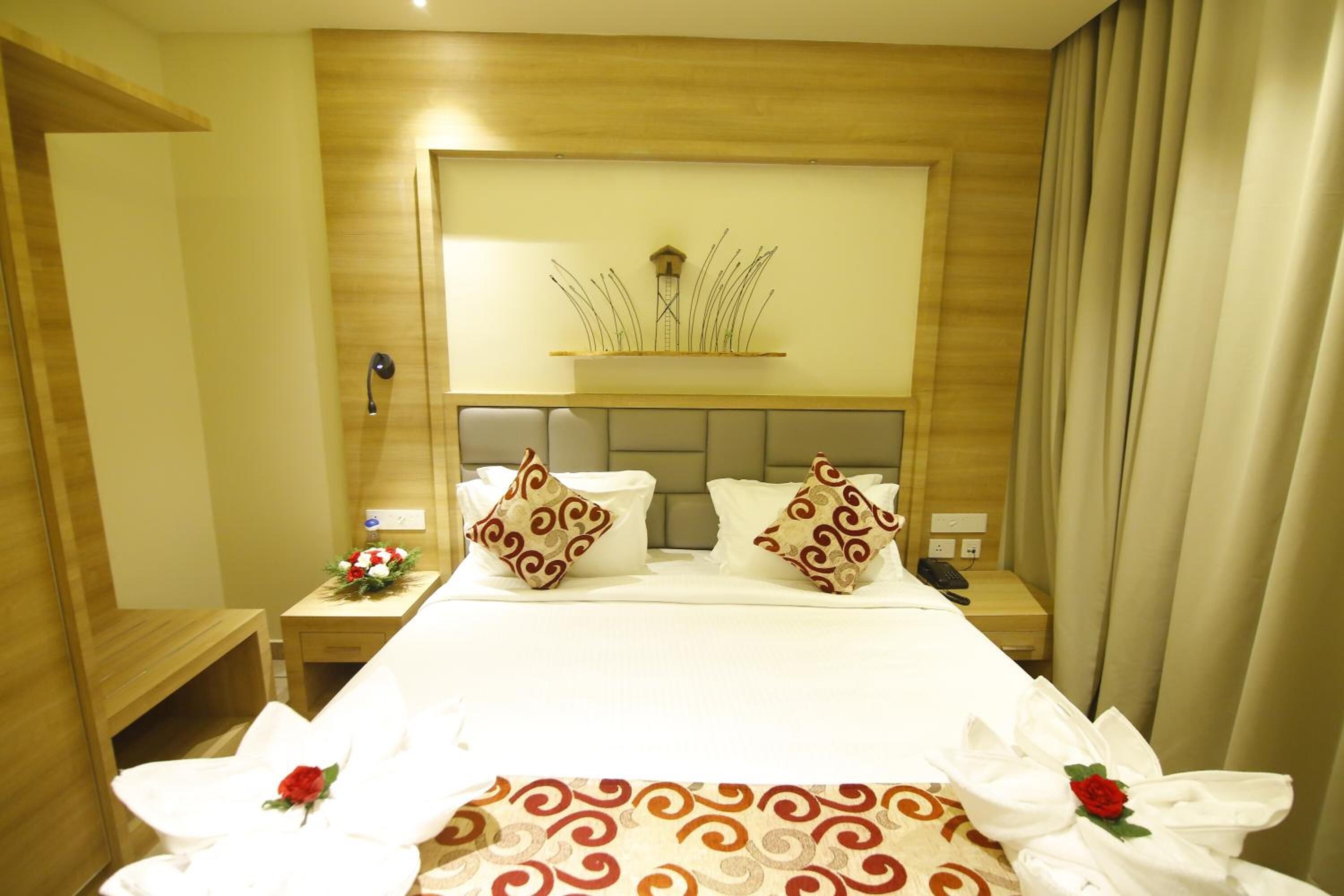 A hotel room with a large bed, wooden headboard, two bedside tables, and a wall-mounted clock.
